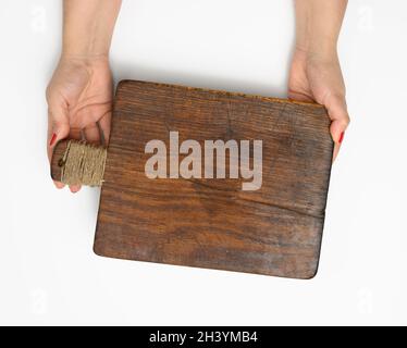 Female hands hold empty rectangular brown wooden chopping board isolated on white background Stock Photo