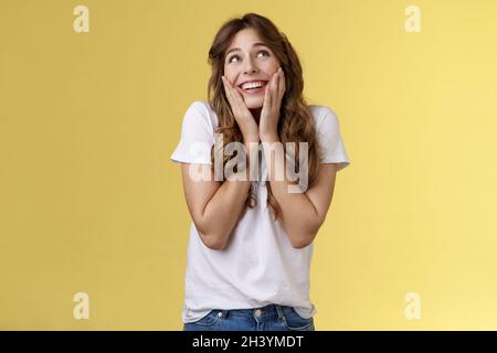 Dreamy flirty feminine cute female curly hairstyle sighing lovely admiration look up smiling broadly touch cheeks blushing recal Stock Photo