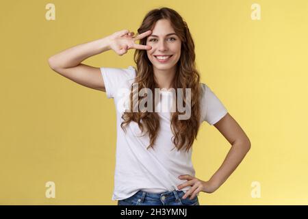 Cheerful positive cute girl curly-haired show peace sign delighted enjoy youth having perfect summer holidays determined rest tr Stock Photo