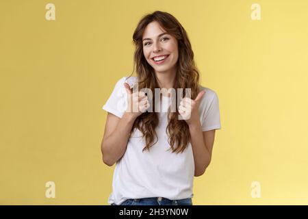 Good have my support. Cheerful positive cute lively curly-haired european girl show thumbs-up approval like gesture tilt head pl Stock Photo