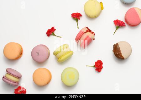 Baked macarons with different flavors and rosebuds on a white background Stock Photo