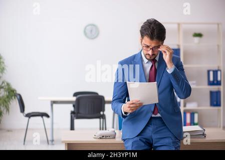 Young male employee reading paper at workplace Stock Photo