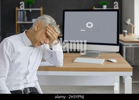 Office worker sitting in front of desktop computer and waiting for system to load Stock Photo