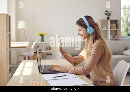 Smiling girl in earphones have video lesson on computer. Stock Photo