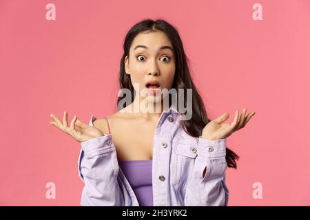 Close-up portrait of speechless, impressed young asian woman, spread hands sideways, gasping and open mouth wide from amazement, Stock Photo