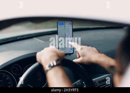 Navigator in car vehicle transportation commuter. Driver man using mobile phone navigator app while driving car Stock Photo