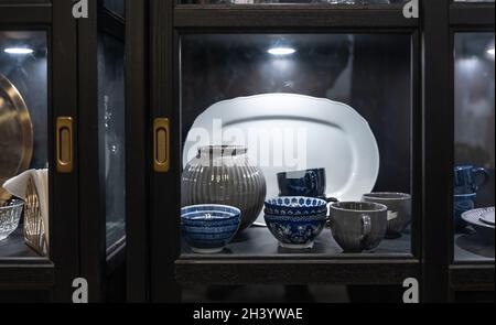 Beautiful vintage tableware in a sideboard behind glass. Stock Photo