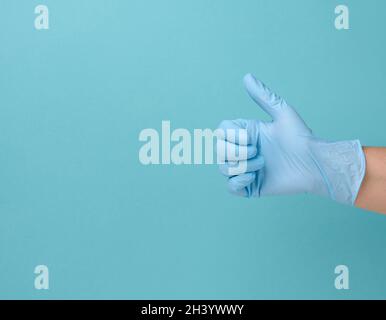 Hand in a blue latex medical disposable glove shows the gesture like on a blue background Stock Photo