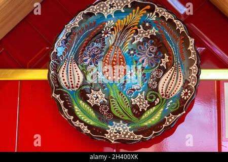 Colorful ceramic painted plates hanging on the red wall Stock Photo