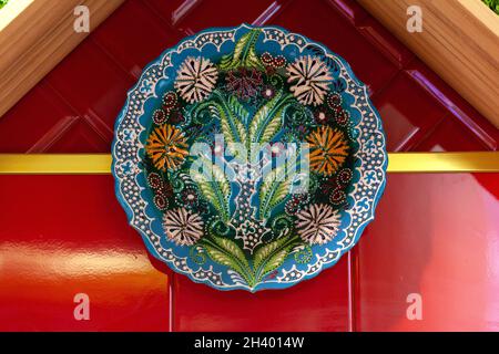 Colorful ceramic painted plates hanging on the red wall Stock Photo