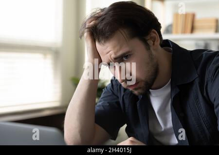 Stressed unhappy young male worker feeling exhausted in office. Stock Photo