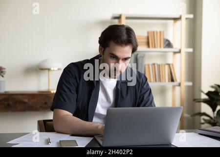 Concentrated young businessman working on computer in office. Stock Photo