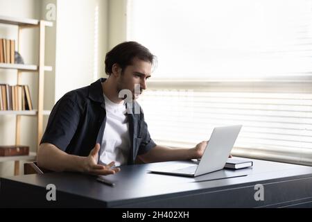 Confused angry young man working on computer. Stock Photo