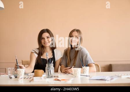 Front view of four beautiful caucasian female at art workshop. A young teacher teaches drawing Stock Photo