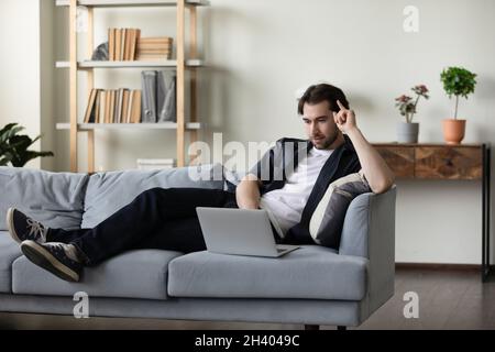Happy relaxed young man using laptop at home. Stock Photo