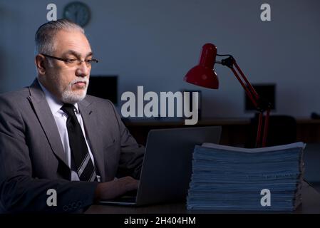 Old male employee working late in the office Stock Photo