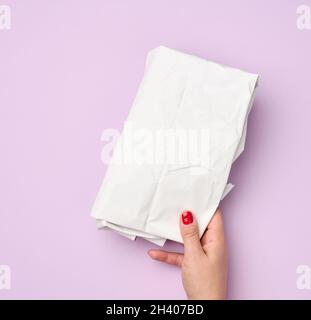 Hand hold folded wrapping crumpled white paper on purple background Stock Photo