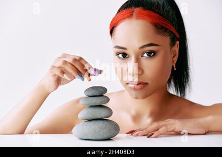 Pretty african american woman doing pyramid of the stones on white background Stock Photo
