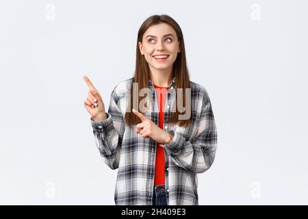 Lifestyle, different emotions, leisure activities concept. Dreamy cute smiling woman in checked shirt, pointing and looking uppe Stock Photo