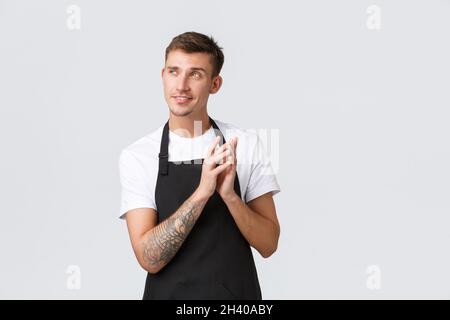 Small business owners, coffee shop and staff concept. Creative and smart handsome sly barista, waiter or cafe employee in black Stock Photo