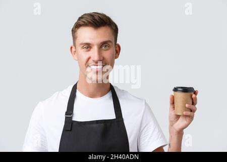 Cafe and restaurants, coffee shop owners and retail concept. Close-up shot of friendly handsome barista, waiter serving takeaway Stock Photo