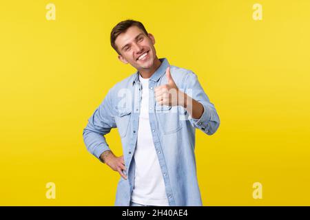 Portrait of satisfied proud young handsome man congratulate person for accomplishing goal, show thumbs-up delighted, smiling ple Stock Photo