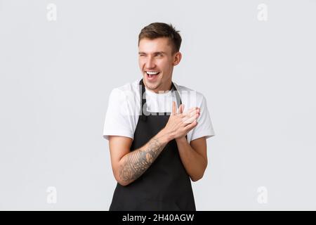 Small business owners, coffee shop and staff concept. Devious and smart funny barista in black apron, cafe worker rubbing hands Stock Photo