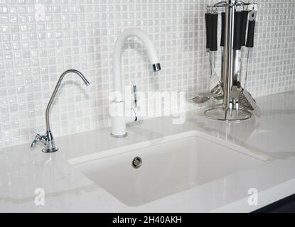 Modern white ceramic kitchen sink. Modern kitchen chrome faucet and mosaic tiles wall Stock Photo