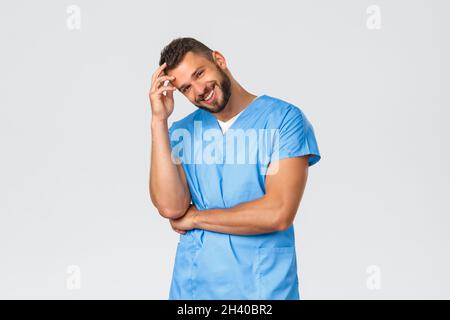 Healthcare workers, medicine, covid-19 and pandemic self-quarantine concept. Handsome hispanic male nurse, doctor in blue scrubs Stock Photo