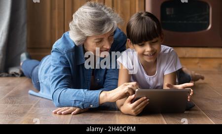 Happy preteen granddaughter kid teaching senior grandmother to use app Stock Photo