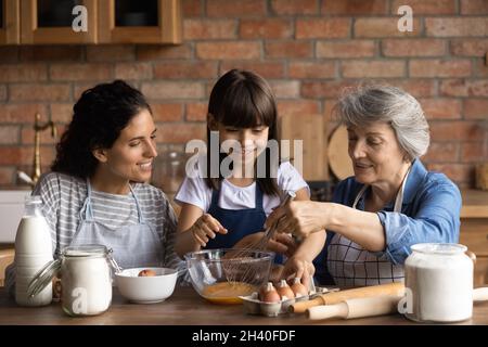 Happy Latin mom and grandma teaching girl to bake Stock Photo