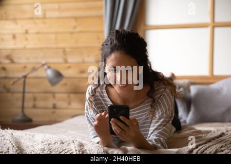 Smiling female smartphone user reading message with good news Stock Photo