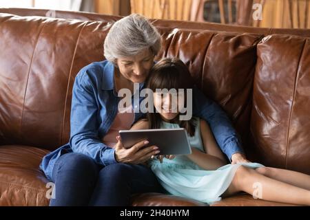 Happy loving older grandma and granddaughter girl making video call Stock Photo