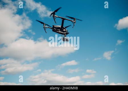 Big quadcopter drone against blue sky aerial flight and filming. Stock Photo