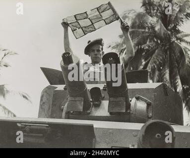 A vintage photo circa 1942 showing a soldier of the 2nd battalion of Argyll & Sutherland Highlanders British Army in a Lanchester 6x4 armoured car gun turret using a flag for signalling.   During the Japanese invasion of Malaya and the fall of Singapore Stock Photo