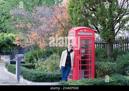 man lean on red telephone box for photoshoot London England UK Stock Photo