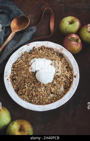 Fresh hot homemade apple crisp or crumble with crunchy streusel topping topped with vanilla bean ice cream. Selective focus with blurred background. Stock Photo