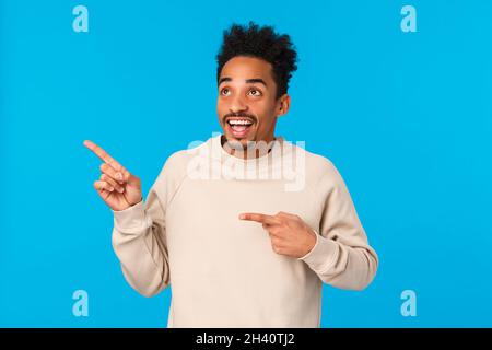 Dreamy inspired and amused, excited smiling african american man seeing first snow, looking at product, company banner, staring Stock Photo