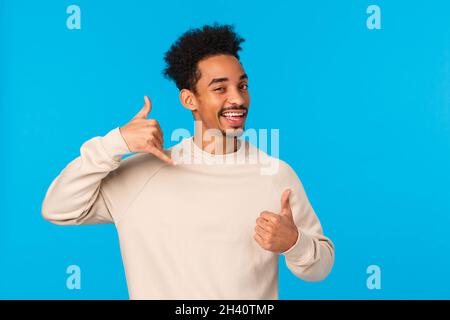 Call me later babe. Sassy and coquettish african-american confident macho guy with moustache, afro haircut showing thumb-up and Stock Photo