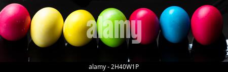 Easter backgrounds. Multicolored Easter eggs on a black background. Banner. Stock Photo