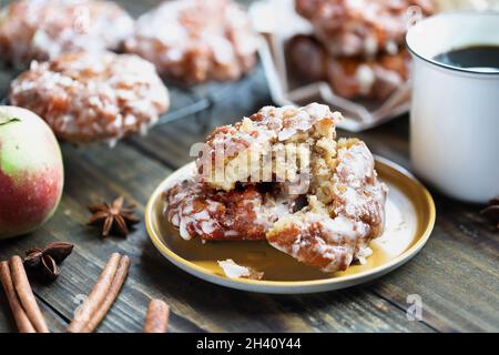 Glazed apple fritters and hot coffee with fresh apples, cinnamon bark and anise. Selective focus with blurred background and foreground. Stock Photo