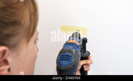 Woman using hand drill in on the wall. Over the shoulder shot. High quality photo Stock Photo