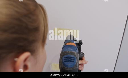 Woman using hand drill in on the wall. Over the shoulder shot. High quality photo Stock Photo