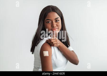 Happy Vaccinated Woman With Adhesive Bandage On Shoulder Stock Photo