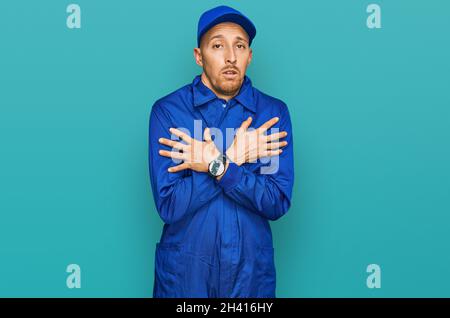 Bald man with beard wearing builder jumpsuit uniform shaking and freezing for winter cold with sad and shock expression on face Stock Photo