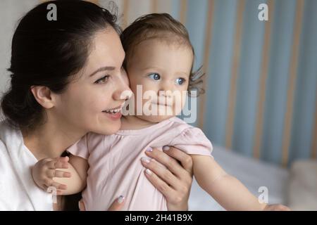 Head shot smiling dreamy mother hugging little daughter, dreaming Stock Photo