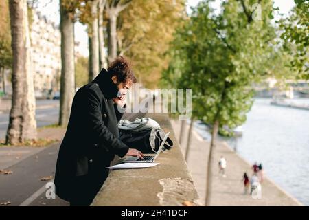 Mulatto businessman discussing new project by smartphone and working with laptop . Stock Photo
