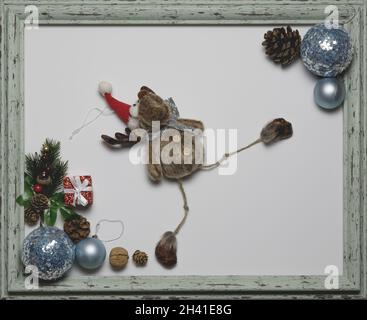 Plush Christmas deer on a white background in a frame with party decorations in the corners Stock Photo