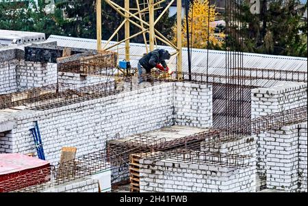 Welder worker welding building metal iron reinforcement elements at the construction site Stock Photo