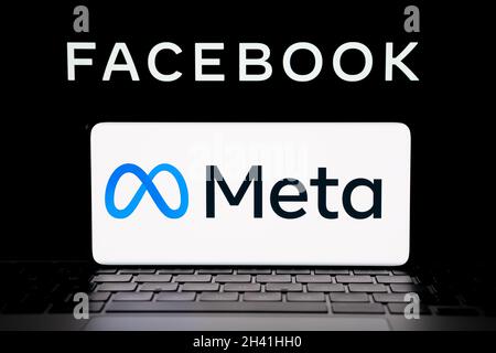 META company logo seen smartphone which is placed on laptop with blurred Facebook inc logo on screen. New Facebook logotype. Stafford, United Kingdom, Stock Photo